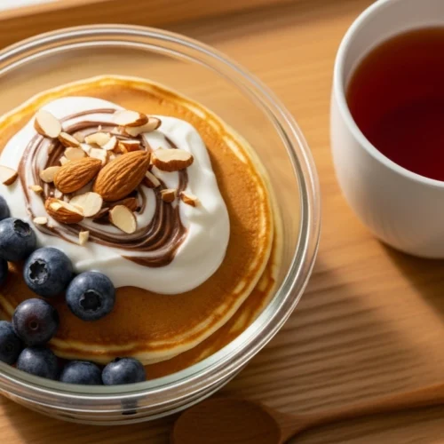pancake bowl topped with yogurt, almonds, and blueberries in glass container